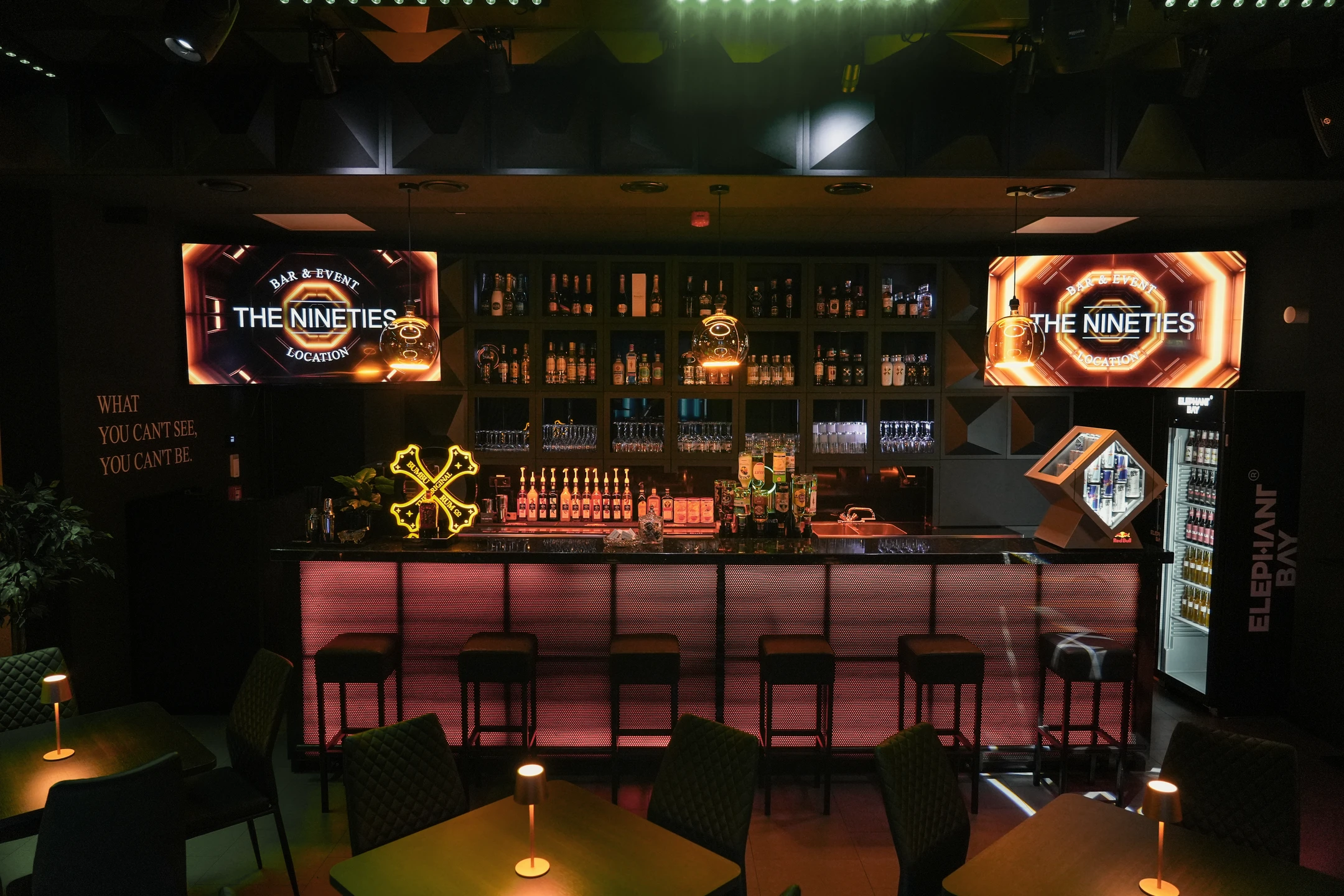 Blick auf die Theke, beleuchtete Flaschen und Sitzplätze der Nineties Bar