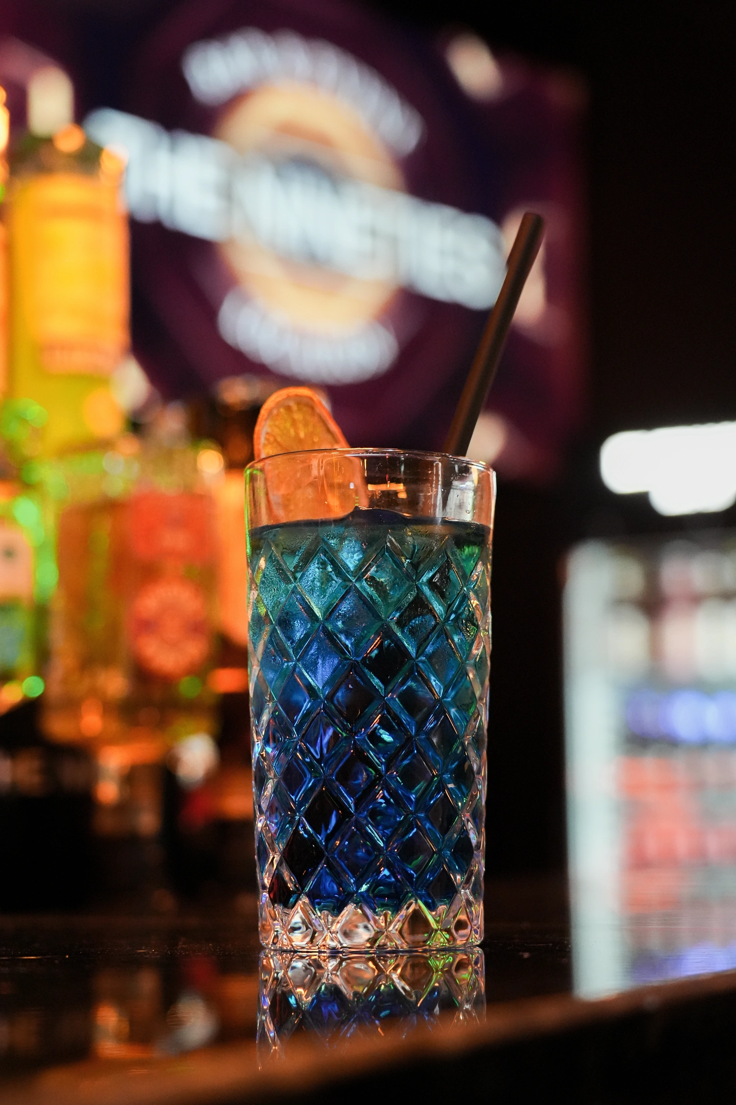 Nahaufnahme eines blauen Drinks vor dem unscharfen Nineties Schriftzug